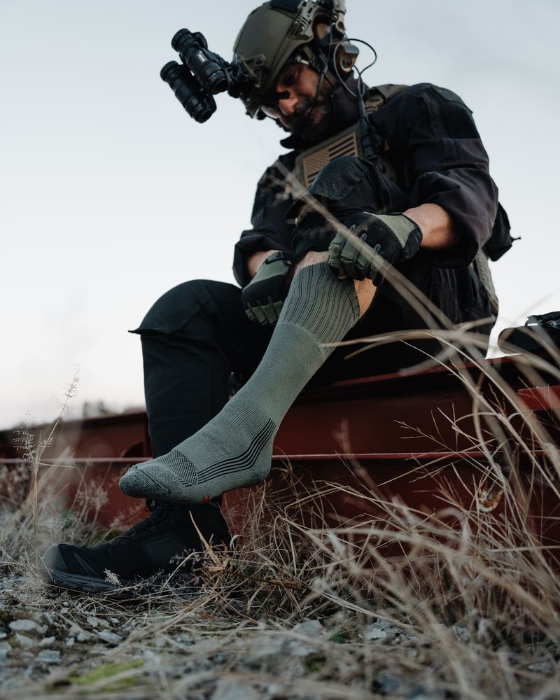 Tactical operator pulling on Fox River military sock in the field